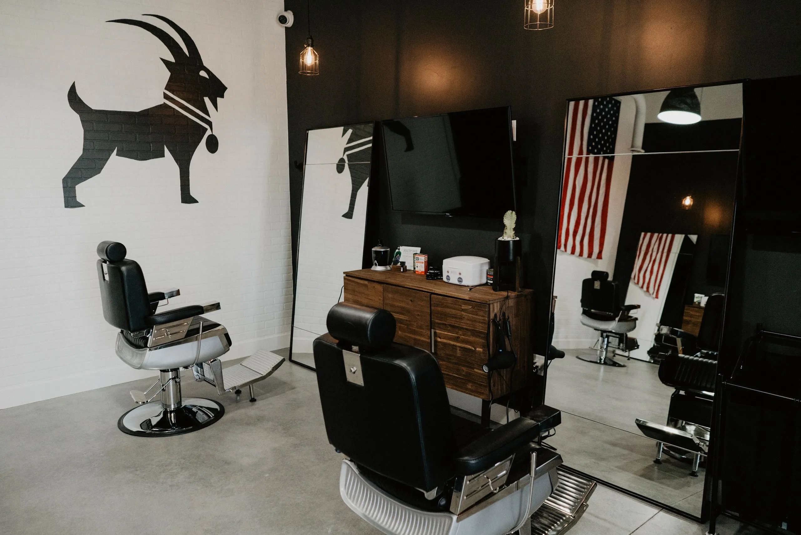 Barber chairs in front of the G.O.A.T. logo wall
