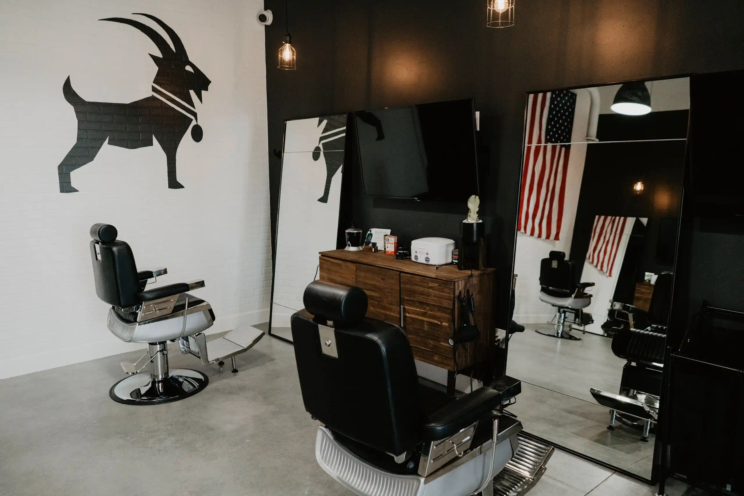 Inside G.O.A.T. Haircuts: barber chairs in front of the goat logo wall