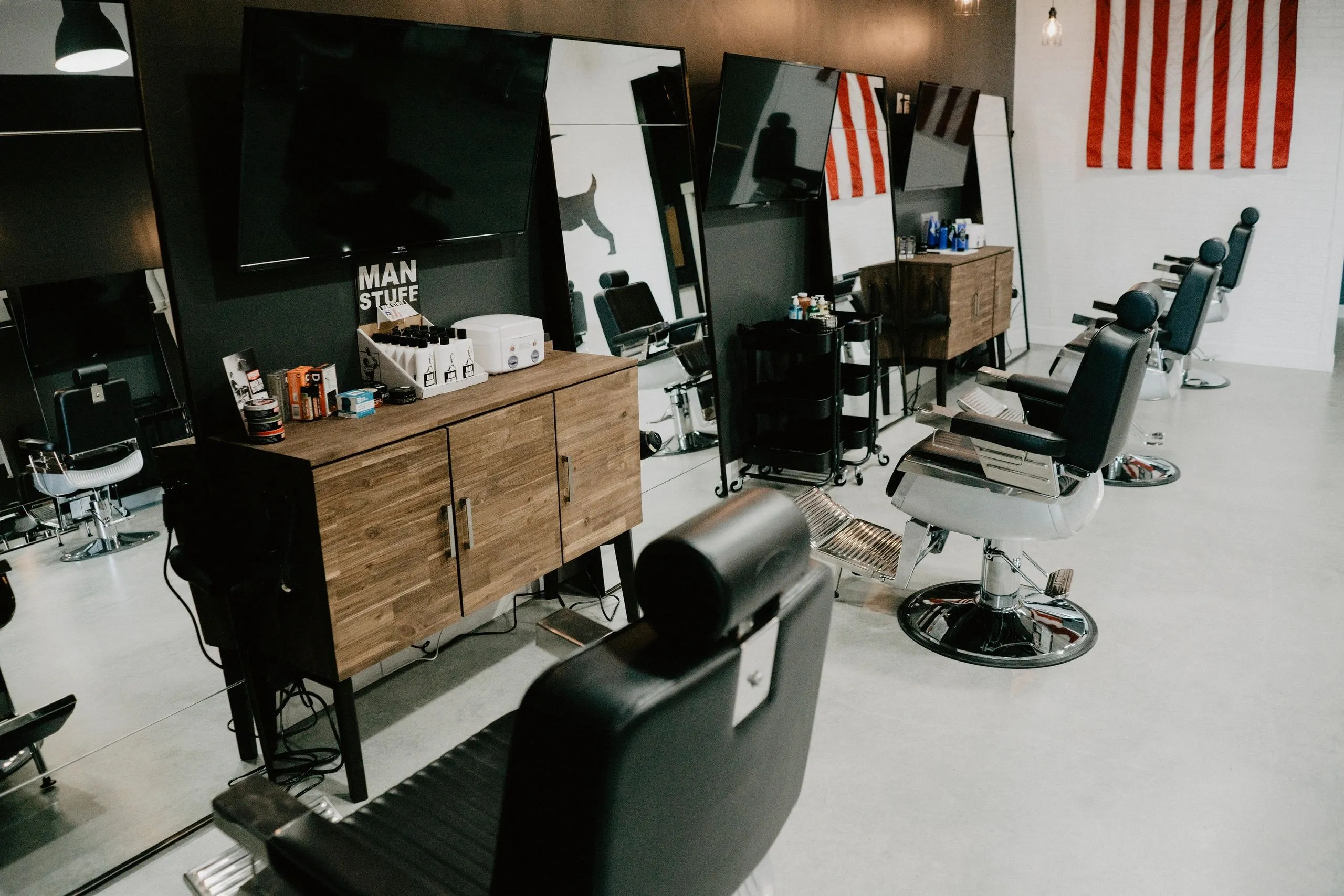 Barber stations under an American flag at G.O.A.T. Haircuts